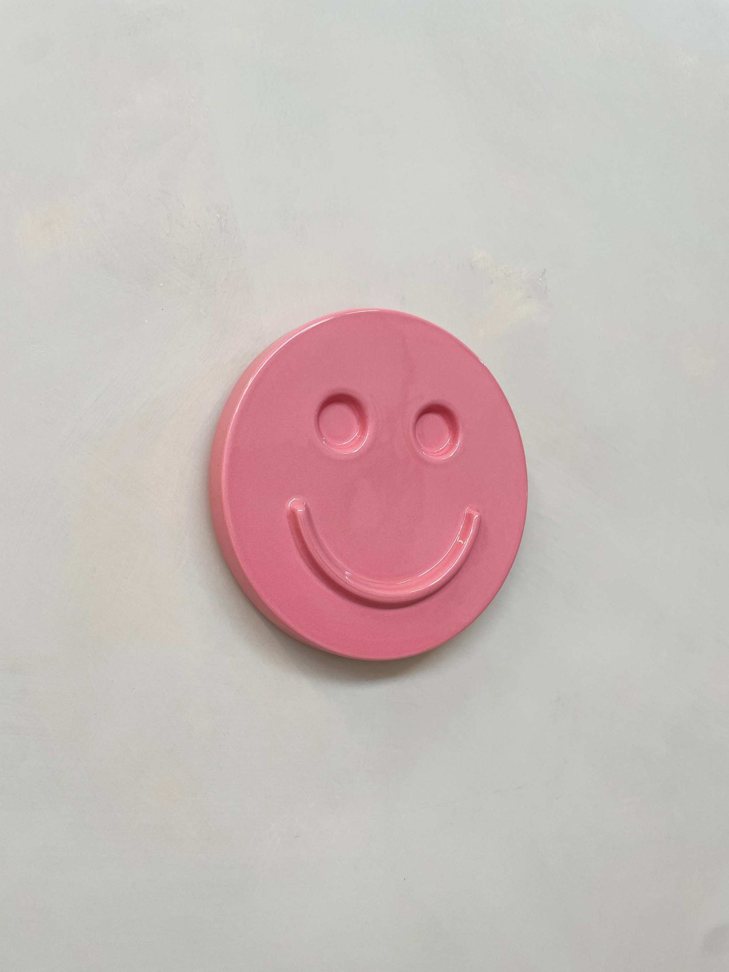 Pink ceramic artwork featuring a smiley face design.