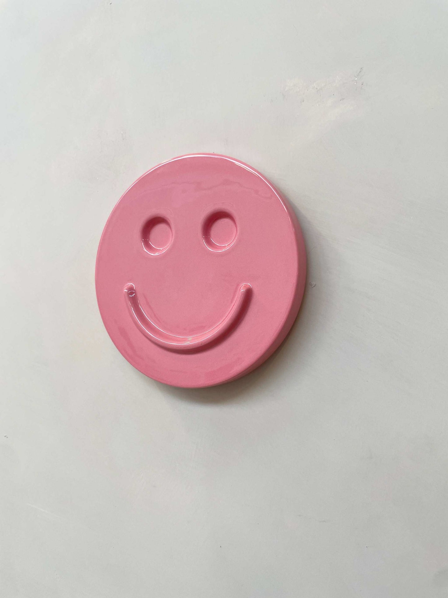 Pink ceramic smiley face artwork by Edith Beurskens.