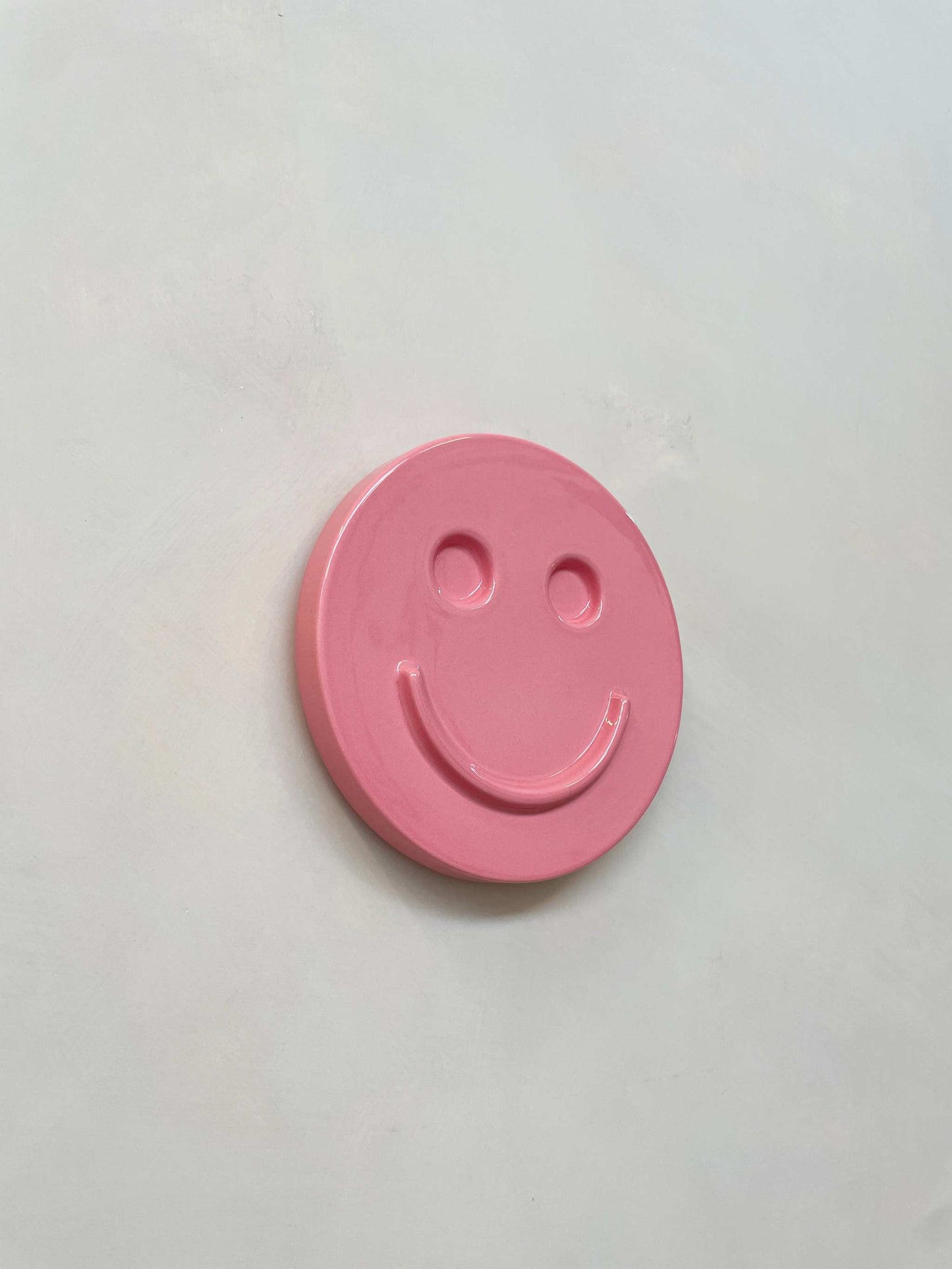 Pink ceramic smiley face artwork by Edith Beurskens.