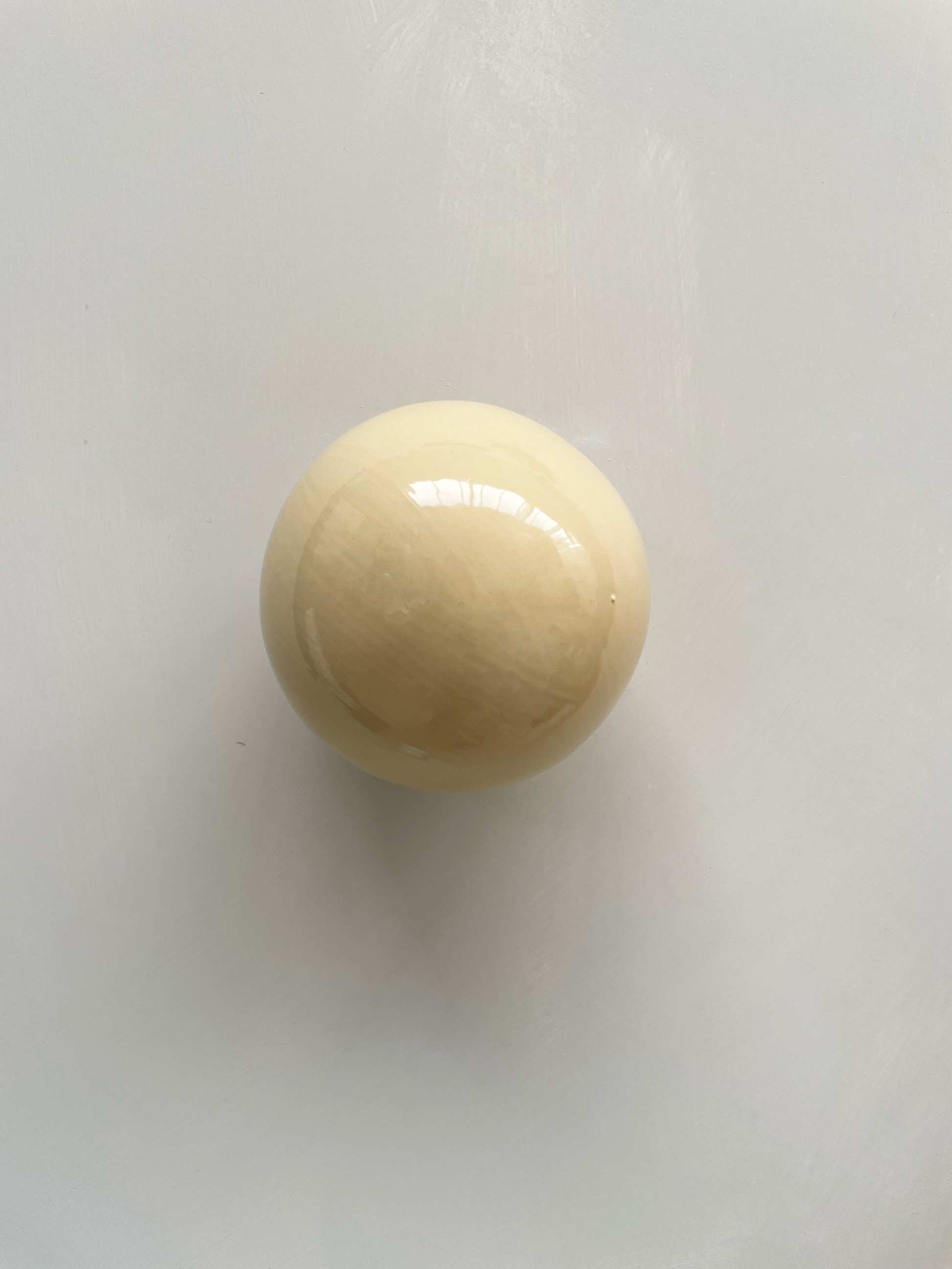 Handcrafted ceramic ball wall sculpture with a light-reflective butter-like surface.