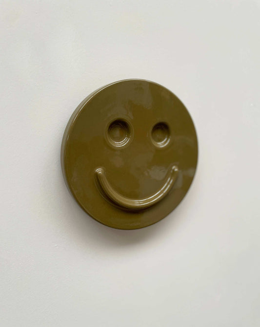 Olive 'HAPPY' ceramic artwork with smiley face design.