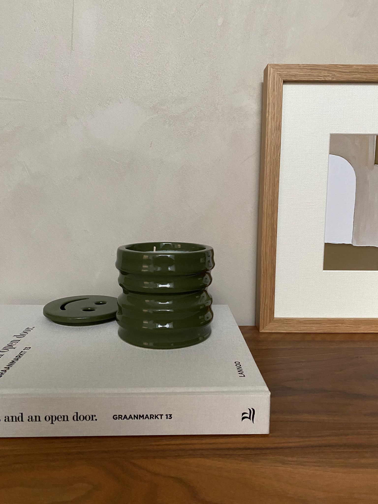 Scented candle in green ceramic holder, part of the Shapes Collection, displayed on a wooden surface.